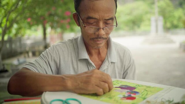 Vietnamese artisan embroidering traditional tapestry outdoors in ninh binh