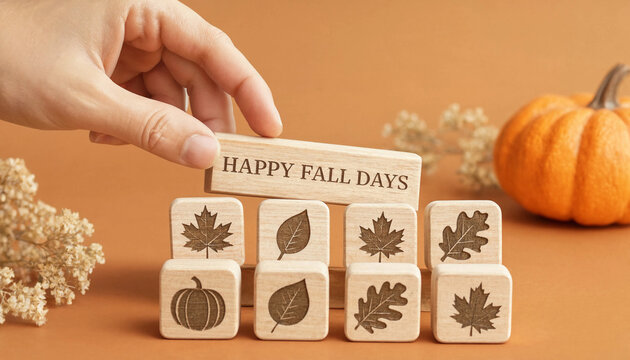 Hand holding wooden block with Happy Fall Days text above leaf and pumpkin blocks