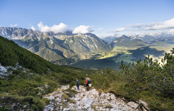 Two hikers on a hiking trail, in the background valley with village Leutasch and summit of the Wetterstein mountain range, descent from Hohe Munde, Mieminger Kette, Tyrol, Austria