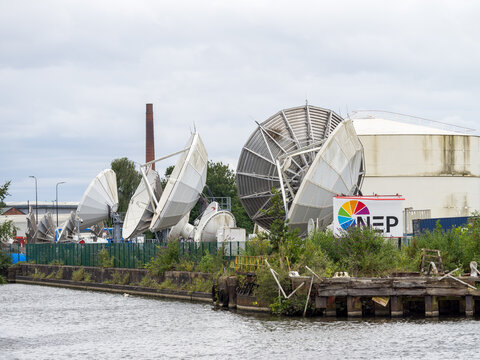 NEP Group satellite dishes transmitting and receiving broadcast signals by canal in industrial Manchester