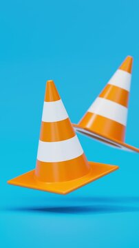 Front view pair of floating traffic cones in orange on a blue background for road safety and construction warning. Vertical video.