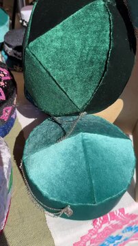 Traditional velvet skullcaps with embroidery and decorations at the fair. Vertical