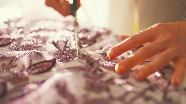 Fashion designer hands cutting sequined fabric