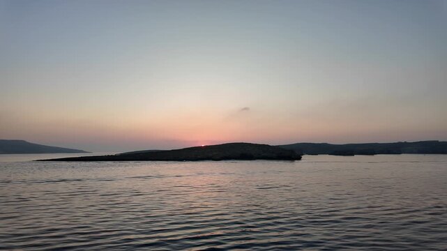 A steady, serene sunset over tranquil water captured with a fixed wide-angle shot from a distance, showcasing the horizon and water surface at dusk. The scene is set in a natural setting.