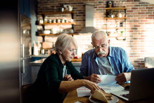 Senior couple reviewing bills at kitchen table