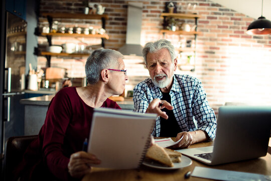 Senior couple discussing finances at home kitchen table