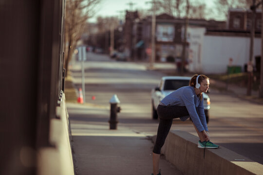Woman runner stretching on city sidewalk before run