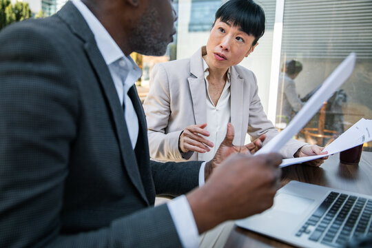 Business colleagues reviewing documents at laptop in modern office