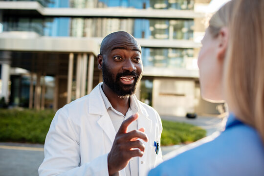 Doctor mentoring nurse outside modern hospital