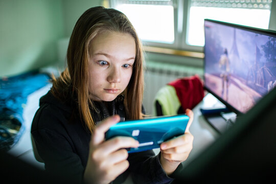 Focused preteen girl playing mobile game at home