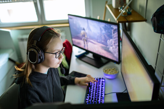 Teen girl with headset playing pc game at home