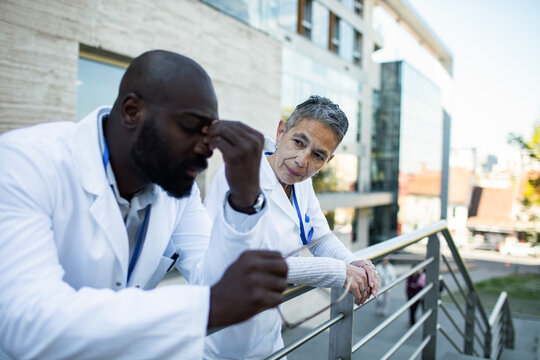 Concerned doctor comforting stressed colleague outside hospital