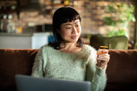 Woman shopping online at home with credit card on sofa
