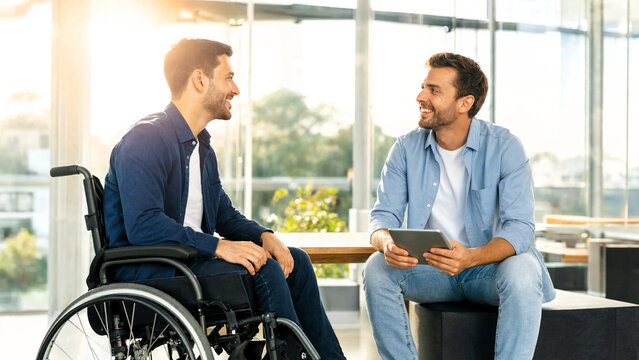 Two men having a conversation in a modern office with a disabled man in a wheelchair