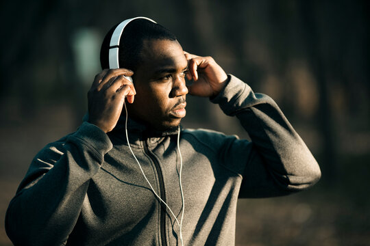Focused man adjusting headphones before outdoor run in park