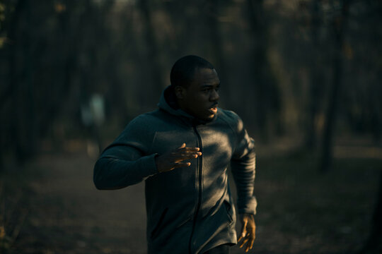 Focused man running on a forest trail at dusk