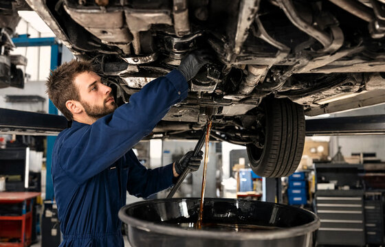 A mechanic in a garage changing the oil in a car