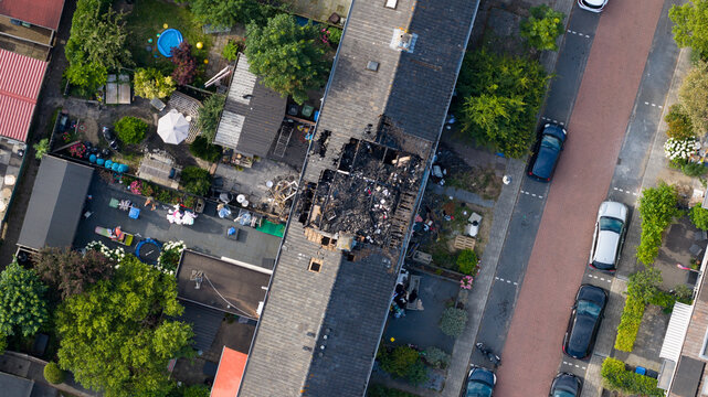 Aerial view of the aftermath of a residential house fire caused by a lightning strike, showing severe roof damage, burned structures and emergency destruction.