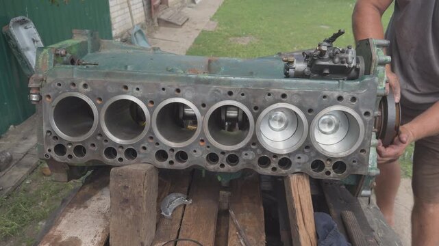 Mechanic rotating crankshaft on old six cylinder engine block