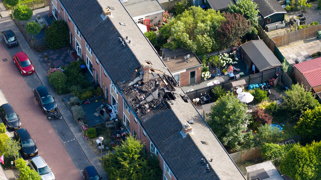 Aerial view of the aftermath of a residential house fire caused by a lightning strike, showing severe roof damage, burned structures and emergency destruction.
