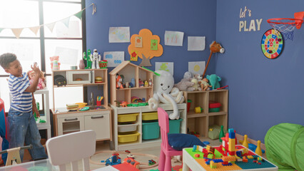 African american boy playing with colorful blocks and reaching hand toward a hoop in a children's playroom inside a building  playful curiosity. © Krakenimages.com