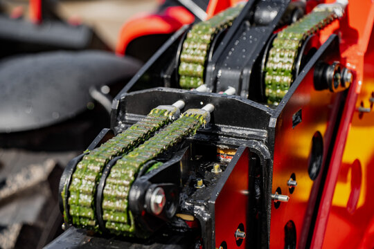 robust metal drive chains on a red industrial machine featuring generous application of green lubricating grease for gear maintenance