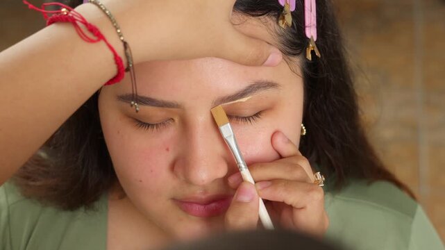 Professional makeup artist applying concealer to eyebrows