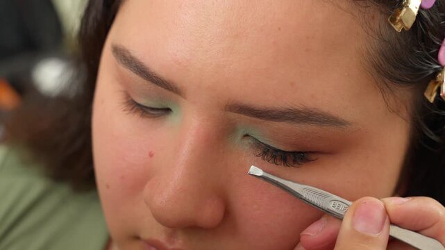 Makeup artist applying false eyelashes in a beauty salon