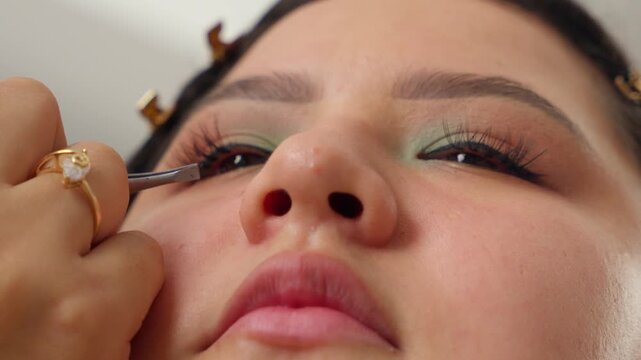Makeup artist applying false eyelashes to a client's eye