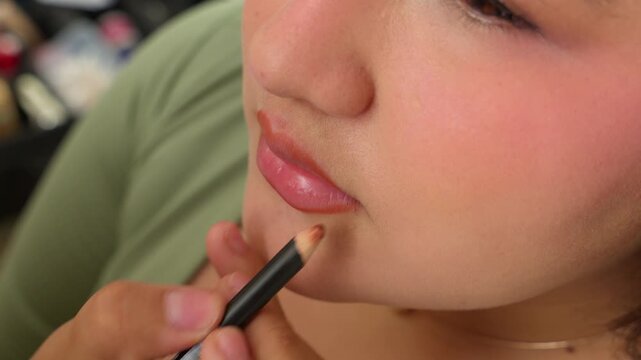 Makeup artist contouring woman lips with a liner pencil