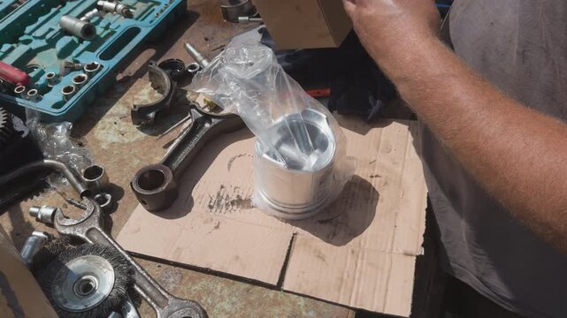 Mechanic unboxing new car engine piston
