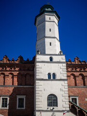 Fototapeta premium Historic white tower and red brick building under clear blue sky