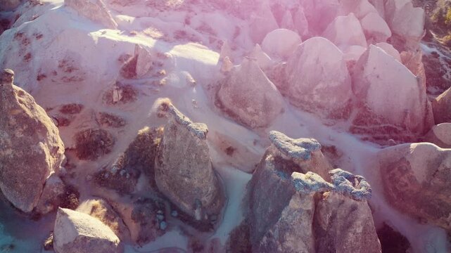 Stunning aerial view of Cappadocia's ancient volcanic landscape and fairy chimneys at sunrise, featuring a beautiful lens flare.