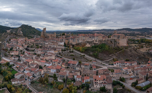 Aerial view of the medieval town of Frias with its historic castle on a rocky cliff, surrounded by stone houses, winding streets, and autumn trees, Frias, Castilla y Leon, Spain.