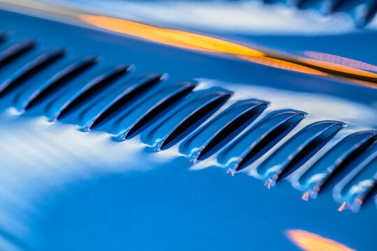 Abstract blue Morgan car hood louvers with warm reflections.