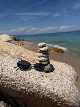 A beautiful photo of round stones against the backdrop of the sea. Glasses against the backdrop of the ocean.