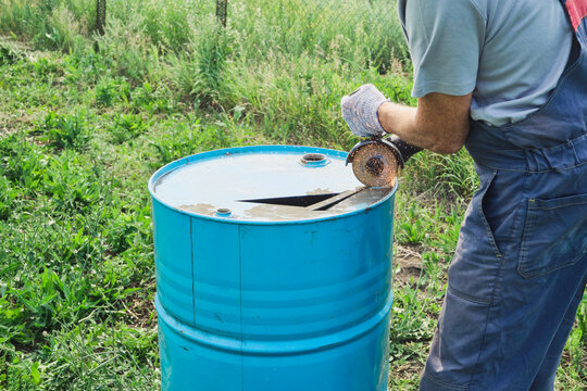 Worker cutting an old steel drum with an angle grinder. Upcycling metal barrel