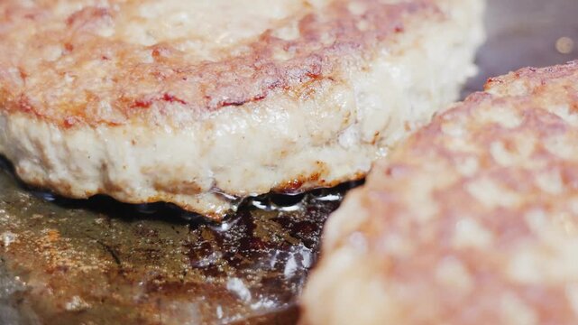 Hamburger patties frying and searing in hot skillet pan