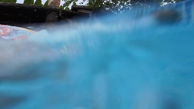 Low view of above ground pool with active return jet creating ripples splashes and surface waves along blue patterned vinyl wall, with pool, water, jet, spray detail