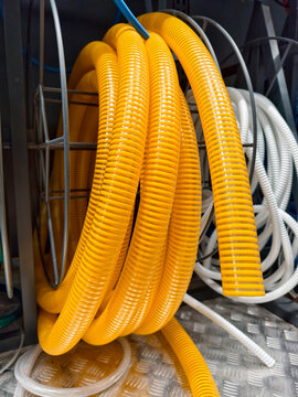 Yellow corrugated hose coiled neatly is displayed on hardware store shelves among construction and utility supply products