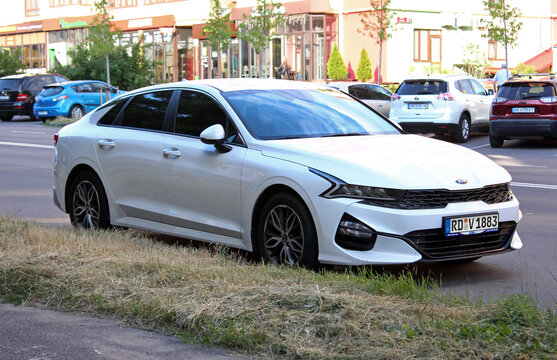 Vinnytsia, Ukraine; April 18, 2026. White KIA K5 2023 at the parking. Sleek, midsize sedan KIA K5 in city street. Korean business car KIA K5 parked on asphalt beside green trees in urban street settin