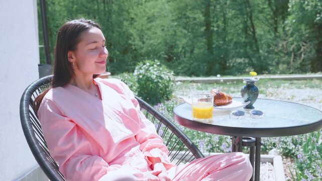 Relaxed woman sitting on a terrace chair and enjoying the sun.
