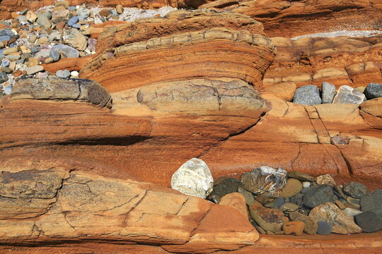 Faszinierende Sandsteinformation mit markanten Sedimentschichten und bunten Kieselsteinen. Hochwertige Detailaufnahme von geologischer Struktur und Erosion f&uuml;r Stockfotografie.