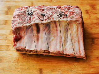 Huge carvery rib roast on the bone is on a wooden cutting board. Butcher craft and skill product. Top quality beef meat with high value and price tag due to premium cut and complicated production. © mark_gusev