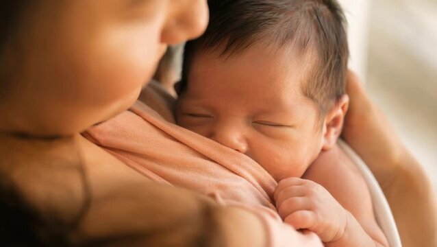 A mother gently cradles her sleeping newborn baby close to her chest during a peaceful breastfeeding moment, celebrating the pure and natural bond of maternal care during world breastfeeding week