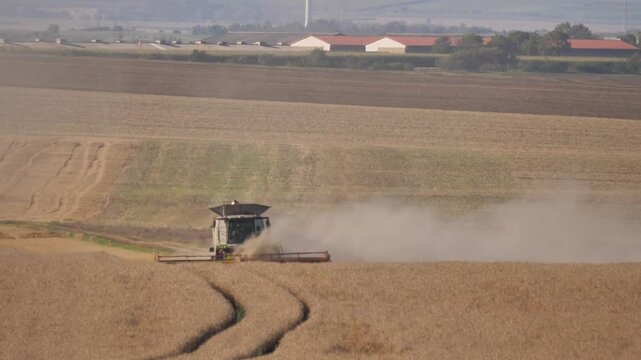 Combine Harvester Harvesting Large Field leaving Dust Trail