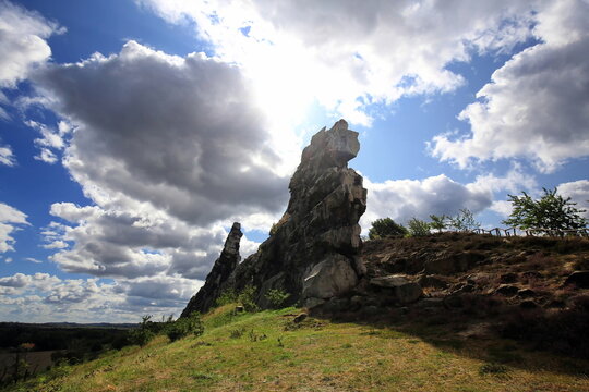Imposante Sandsteinfelsen der Teufelsmauer im Harz. Eine markante Felsformation mit einer freistehenden Felsnadel vor blauem Sommerhimmel mit wei&szlig;en Wolken. Ideal als Naturbild.