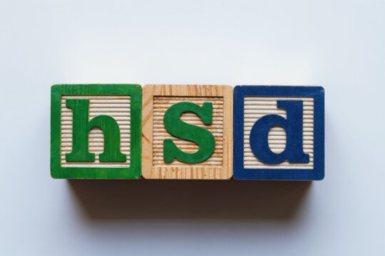 Three colorful wooden blocks spell the word HSD. Blocks have green blue and natural wood colors. Letters are green blue and green. Isolated on white.