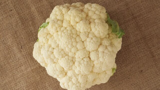 Fresh organic cauliflower rotating on burlap background