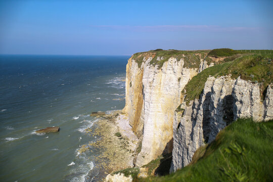 Chalk cliffs of &Eacute;tretat rise dramatically along the Normandy coastline, France, shaped by wind and sea erosion, forming arches, needles, and white walls overlooking the English Channel waters below to